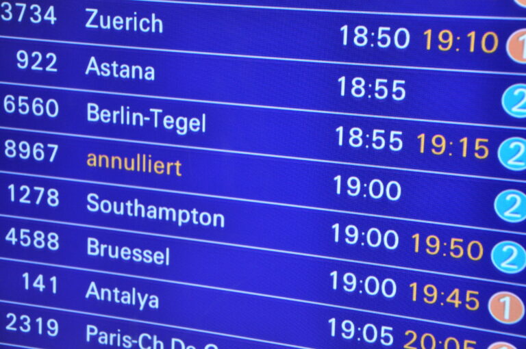 Flight information board listing cities (Zurich, Astana, Berlin-Tegel) with corresponding departure times (e.g., 18:50, 18:55). - Kanzlei Hotes